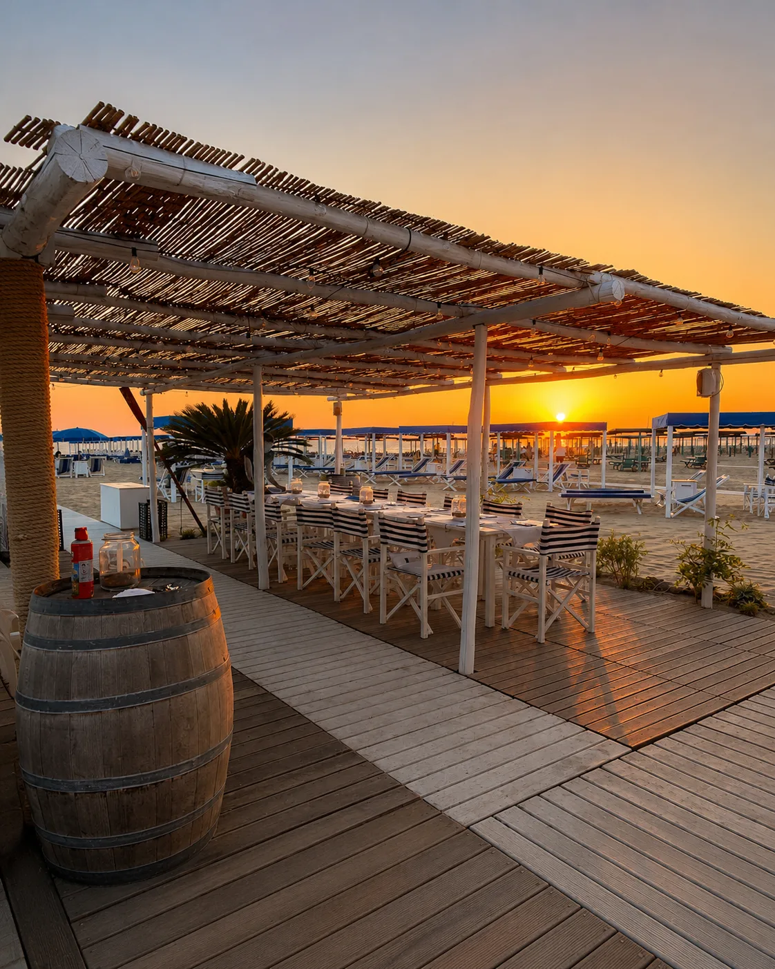 Tavoli del ristorante del Bagno Carla con botte di legno e palma al tramonto, Forte dei Marmi