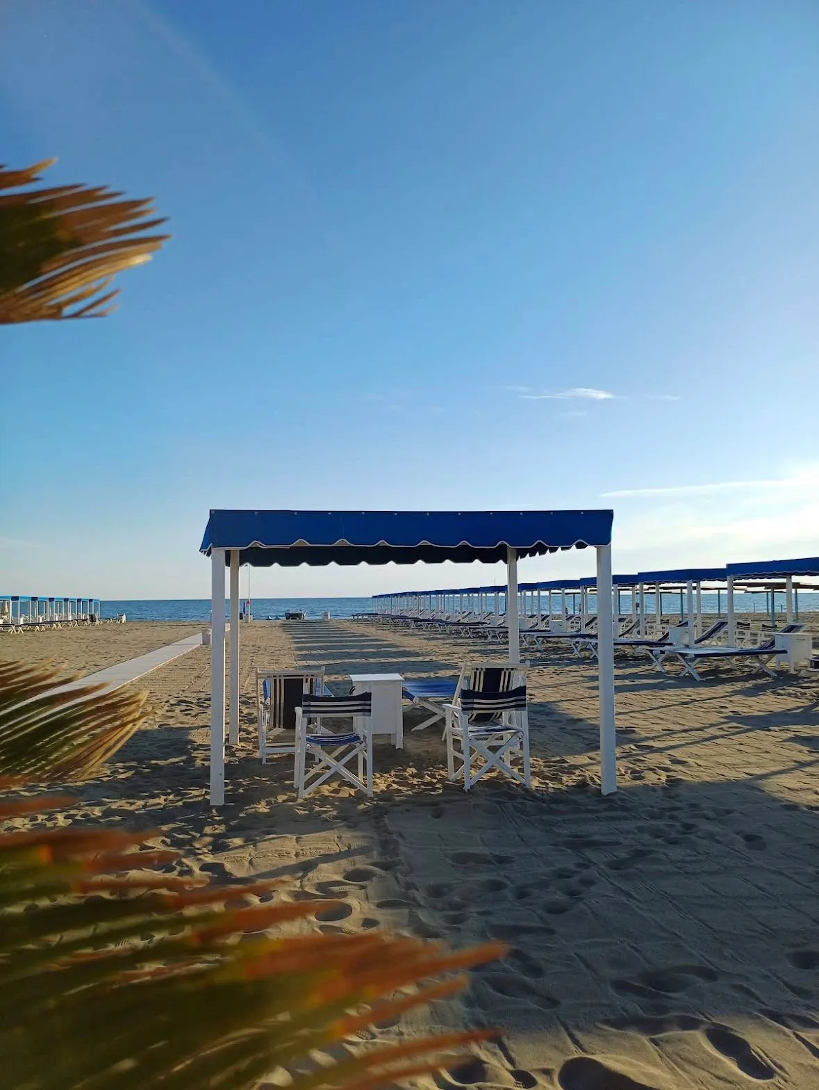 Gazebo blu sulla spiaggia del Bagno Carla nella luce dorata della sera, Vittoria Apuana